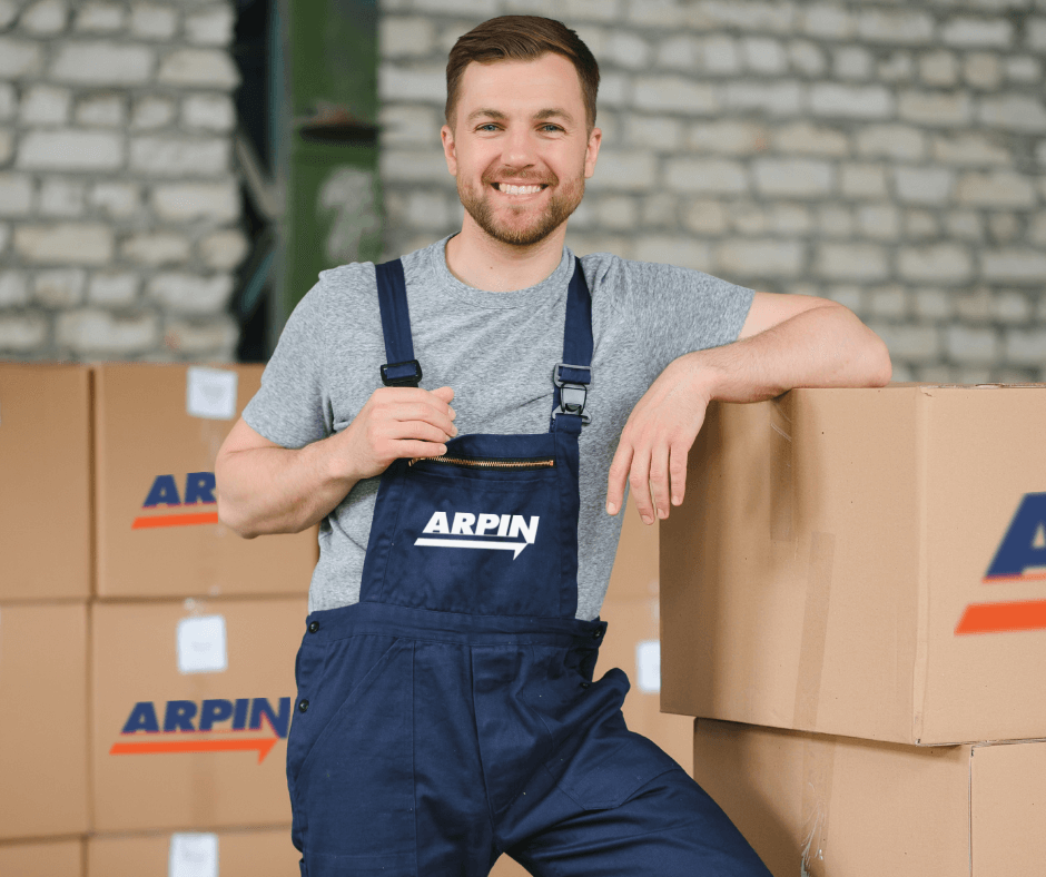 Arpin German mover and packer smiling in the living room with packed Arpin boxes. The mover is one of the responsibles for moving to Germany and moving from Germany.