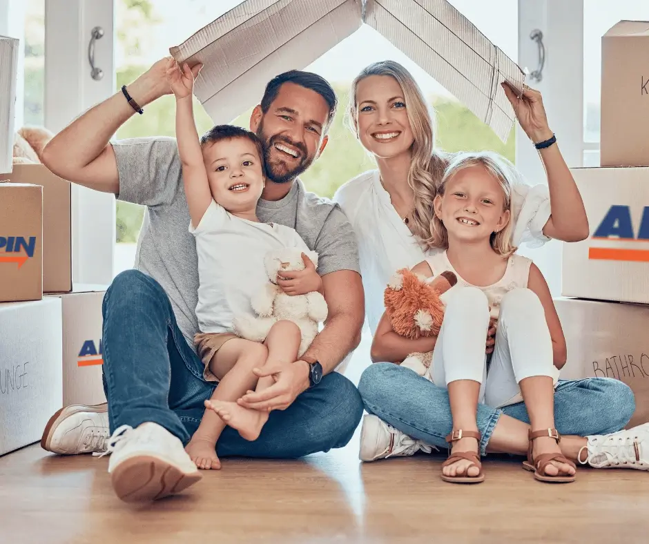 Happy family sitting on floor with Arpin-branded boxes in the background. Arpin Ireland Movers provided exceptional moving services.